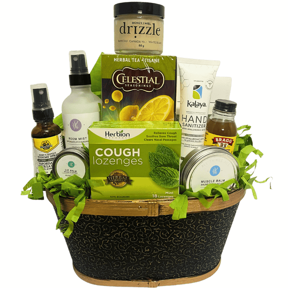 A gift basket containing various self-care items including honey, herbal tea, bath bombs, muscle balm, lip balm, room mist, hand sanitizer, and throat spray.