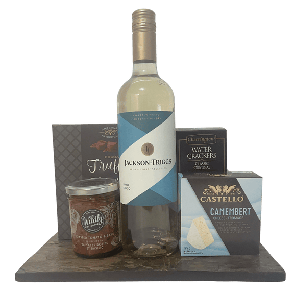 Bottle of Jackson Triggs wine with Camembert cheese, crackers, chocolates and bruschetta on a slate board.