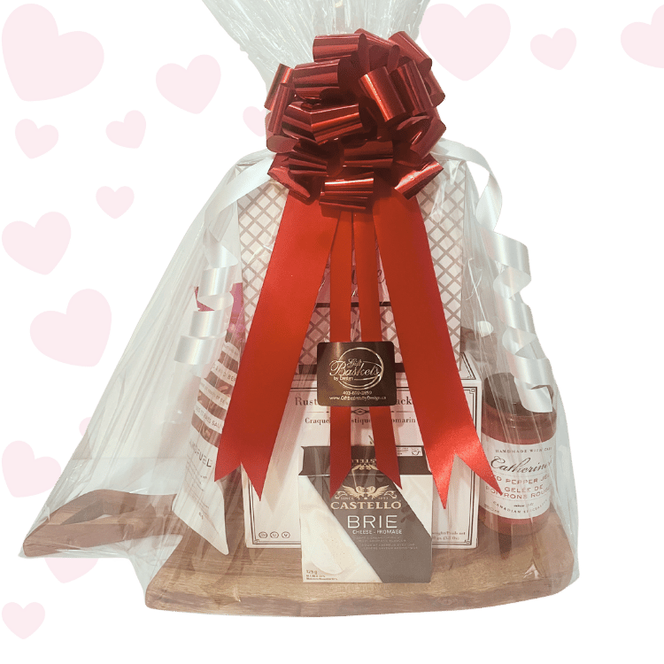 Love at First Bite Valentine’s charcuterie gift basket with gourmet crackers, brie cheese, chocolates, salmon, and sweet treats, beautifully packaged in cellophane with red ribbons and bow for Valentine’s Day