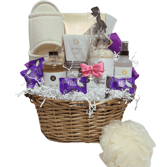 Luxurious gift basket wrapped in pink and purple, featuring Calgary-made bath products, a jar candle, assorted chocolate truffles, spa slippers, and a loofah.