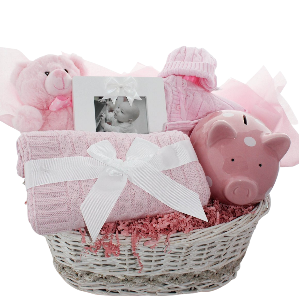 Hello Little One baby gift basket with sweater set, piggy bank, teddy bear, photo frame, and cable knit blanket in a wicker basket, shown in pink