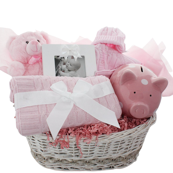 Hello Little One baby gift basket with sweater set, piggy bank, teddy bear, photo frame, and cable knit blanket in a wicker basket, shown in pink